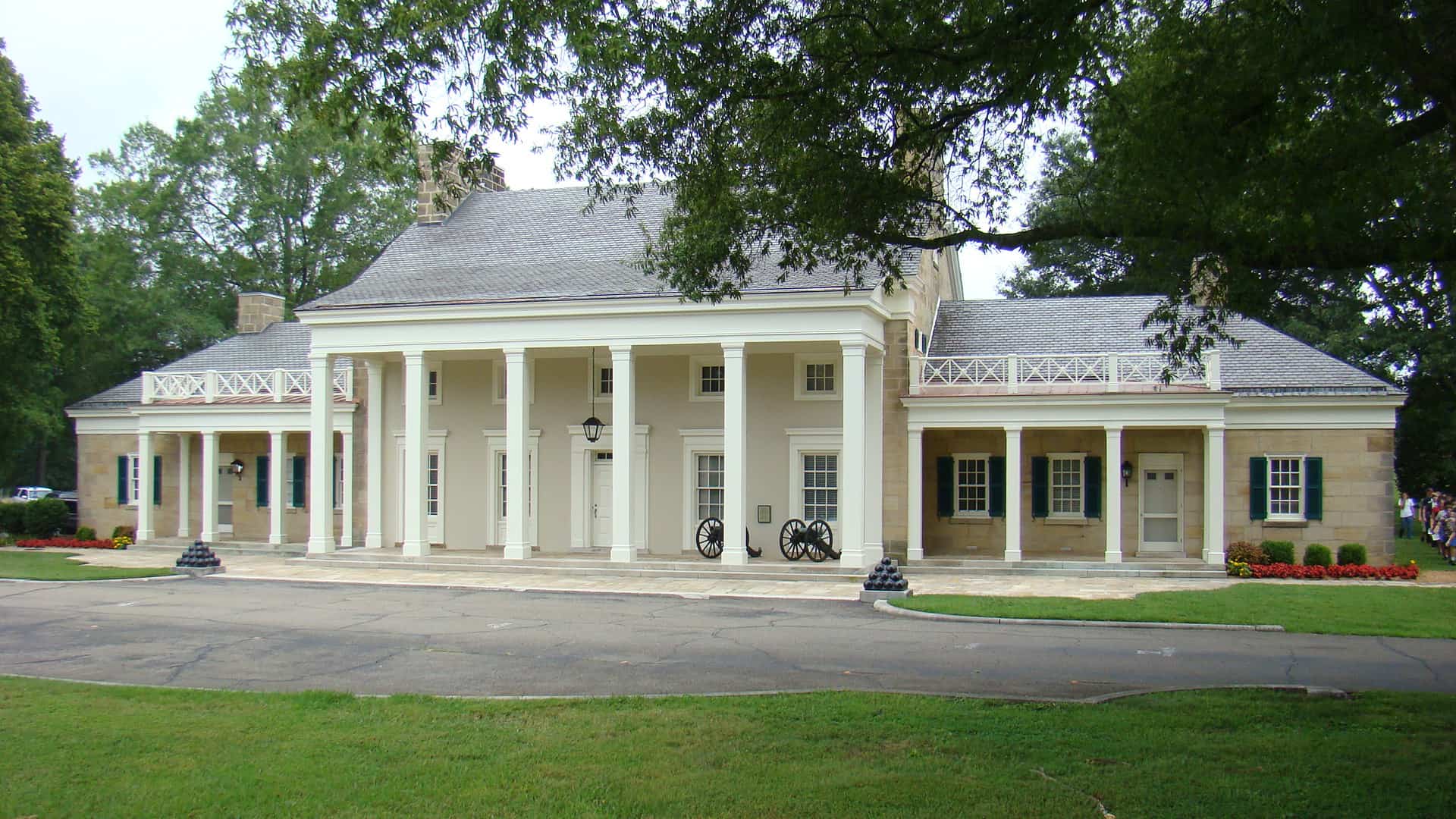 A large white historical building at Chickamauga Battlefield. Canons ad canon balls, tall white columns, and a grey roof. 