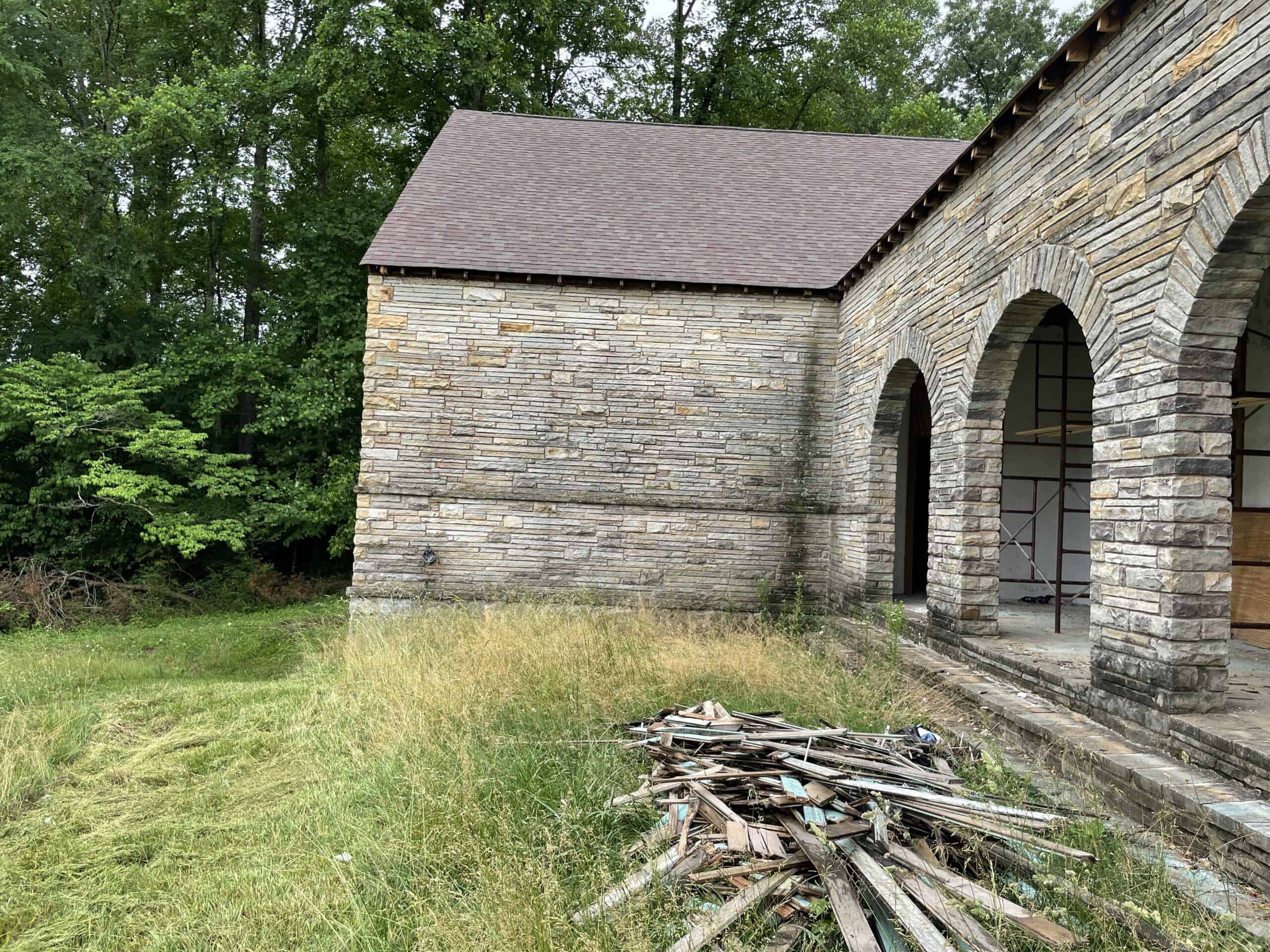A photo from HK’s visit to the historic York Bible School in Pall Mall, Tennessee. An old stone and brick building with a pile of old wood from construction. This is an HK Architects Historic Preservation project under the State of Tennessee Historic Architectural Consultant. 