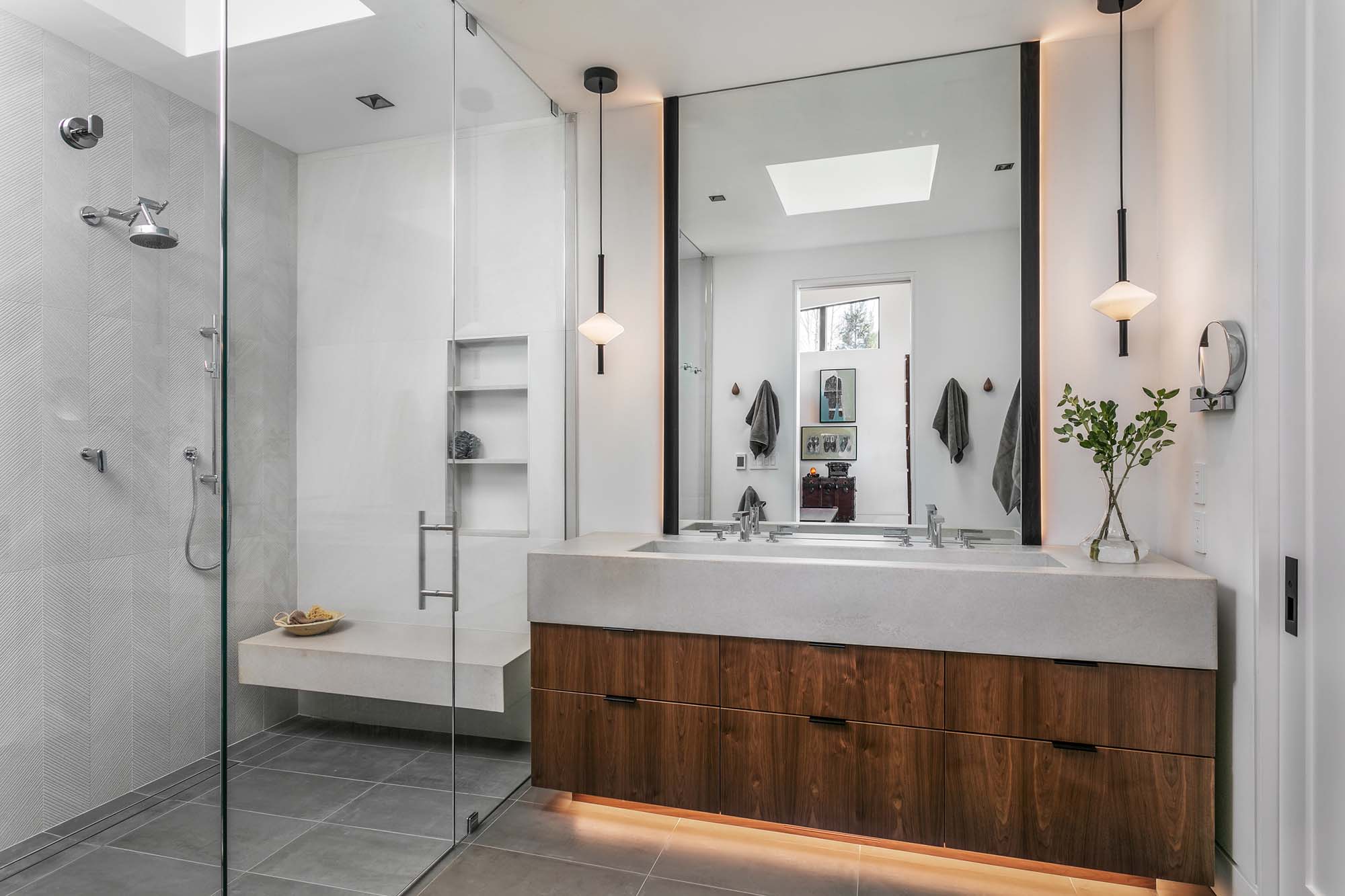A modern bathroom with concrete, walnut, and tile finishes. 