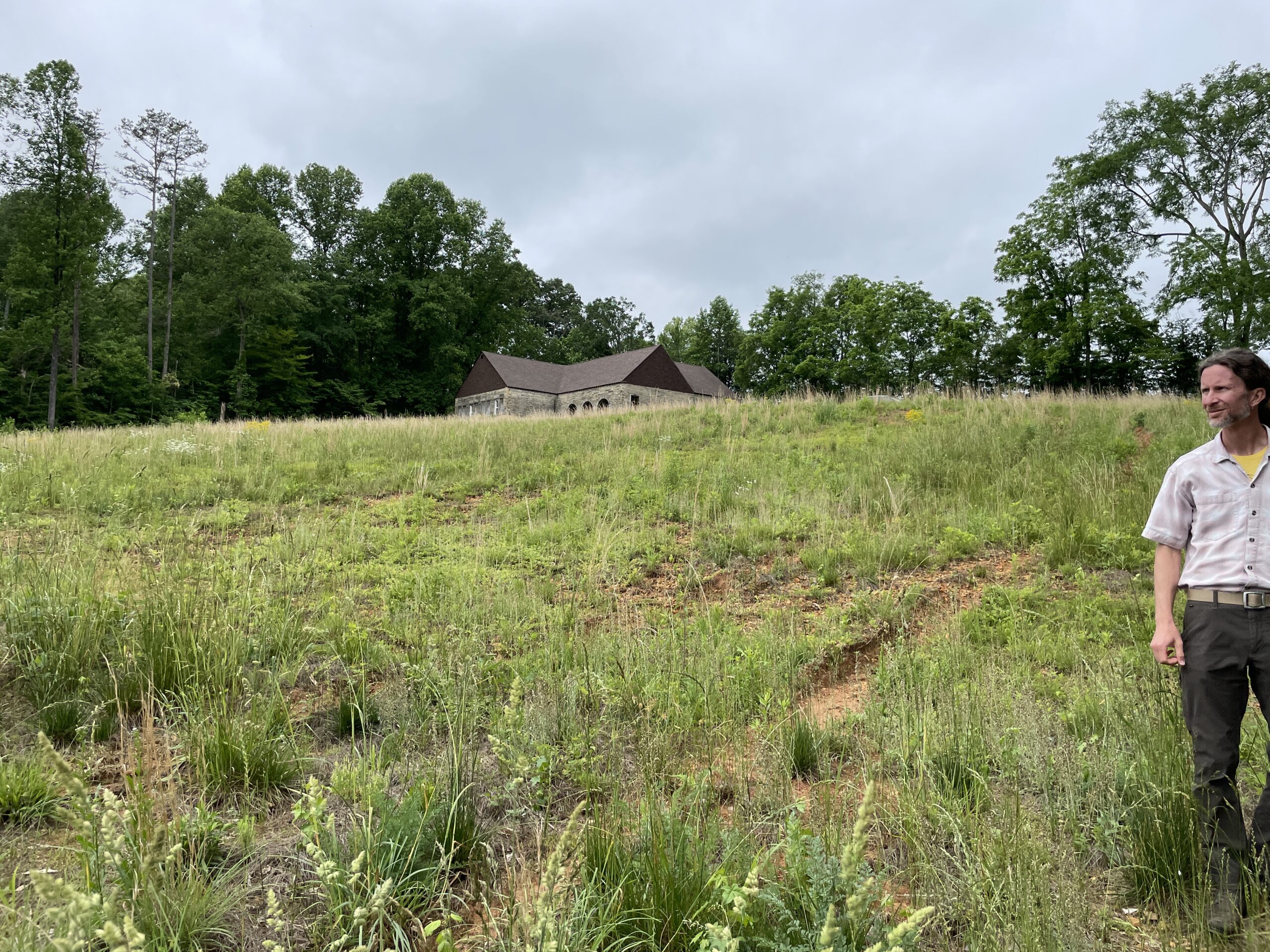 Architect Clif McCormick of HK Architects stands in a field next to a historic Tennessee structure, the York Bible School.