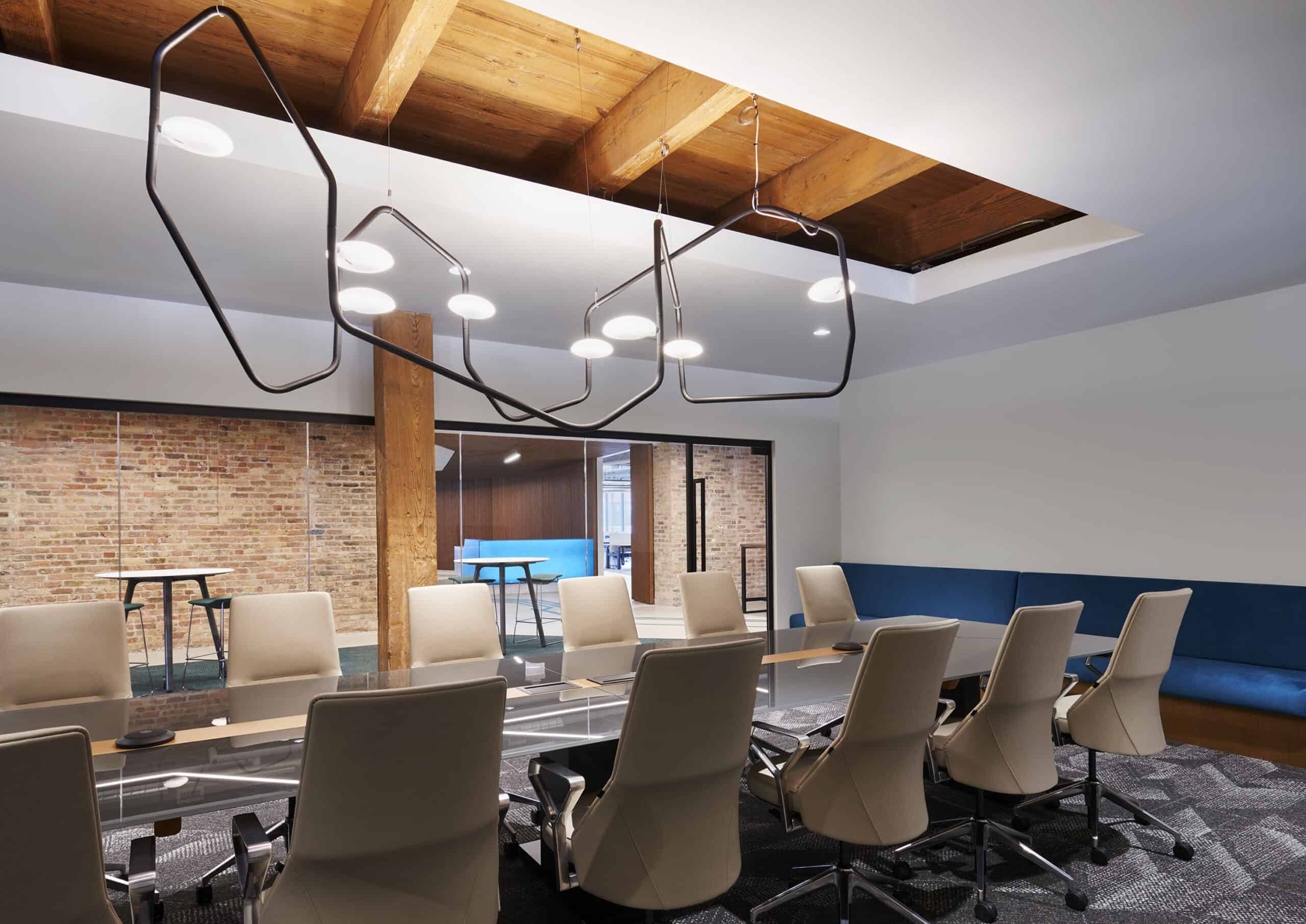 Large modern conference room designed by HK Architects with curved lighting fixture and high back office chairs. 